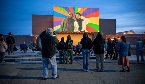 People watching a film projected on a building.