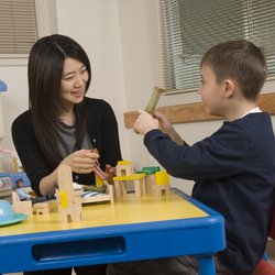 An adult playing with a child during therapy session.