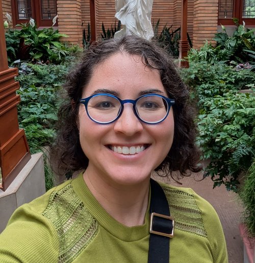 Gabriella Reynolds with blue rounded glasses and a green shirt