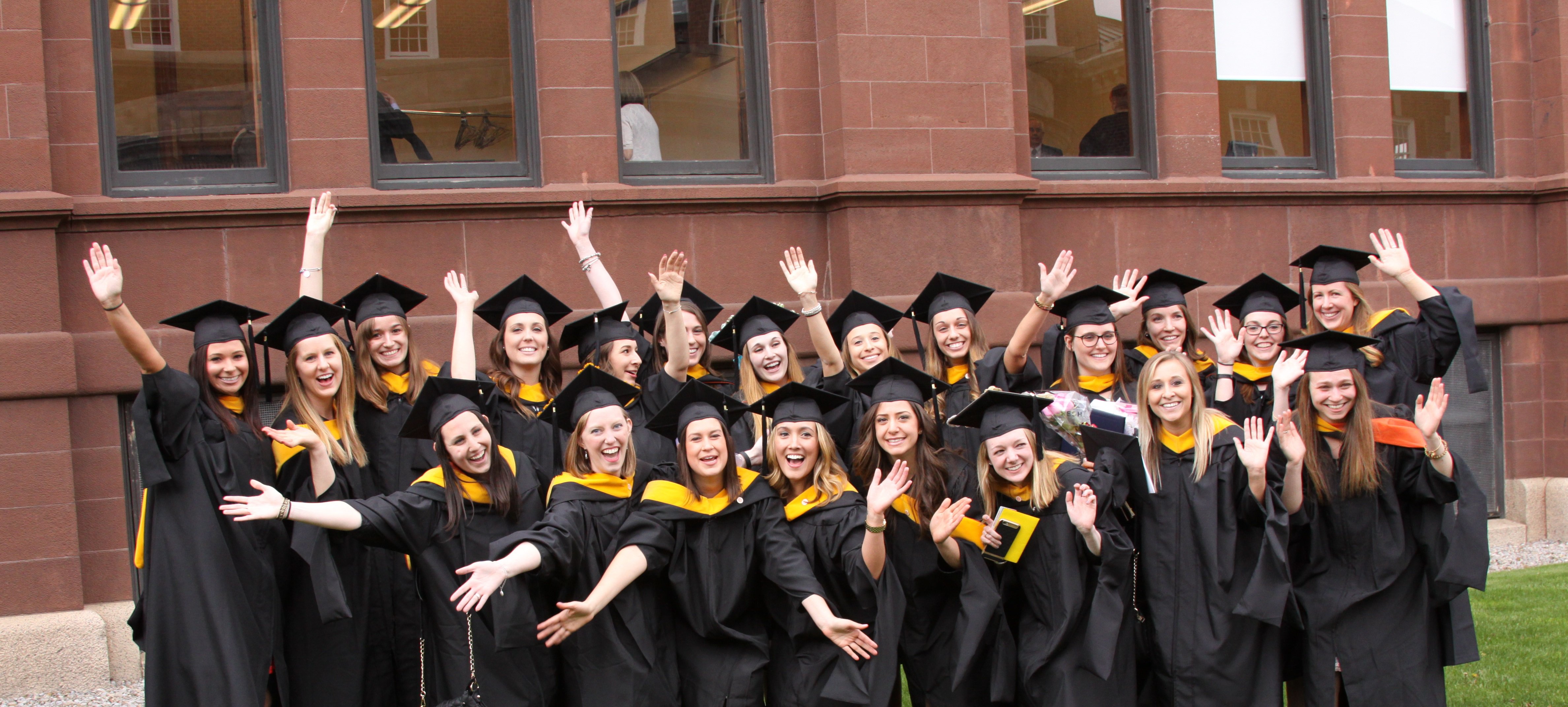 Graduates in regalia in from of Crouse Hinds College