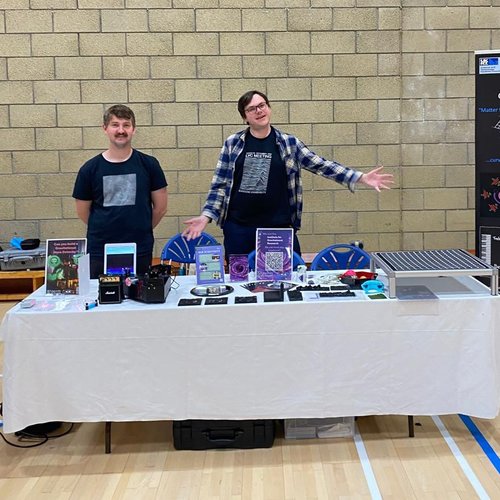 Two people standing behind a table presentation.