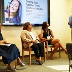 Three people seated and one person standing and talking at a lectern.