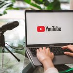 Hand using a laptop with screen displays the Youtube app icons on Apple Macbook Air.