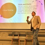A man gives a lecture in front of a screen.