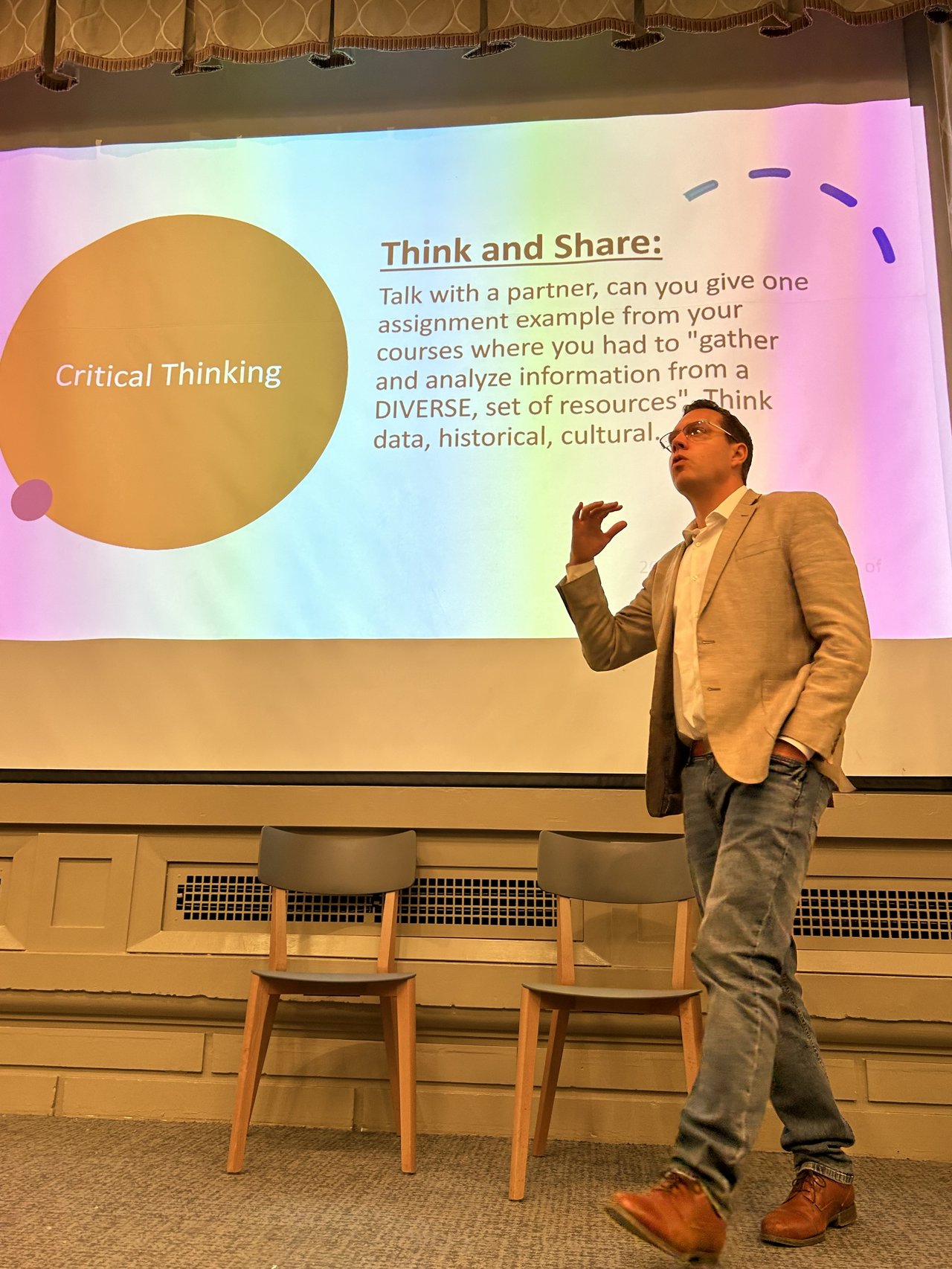 A man gives a lecture in front of a screen.