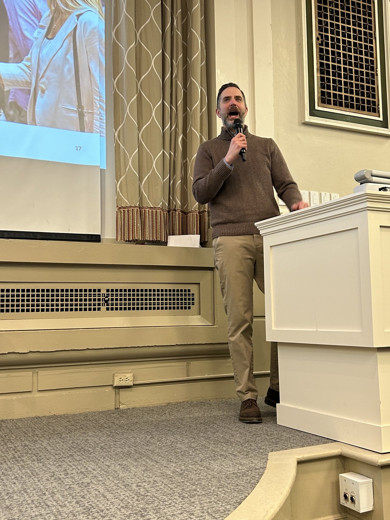 A man behind a podium speaks to a lecture hall.