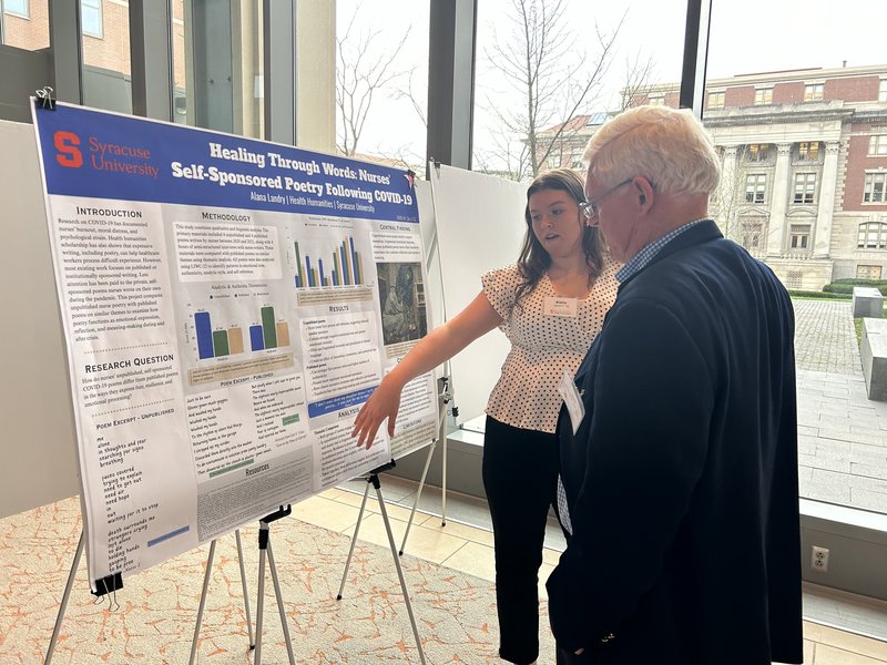 A student presents a research poster to a board member