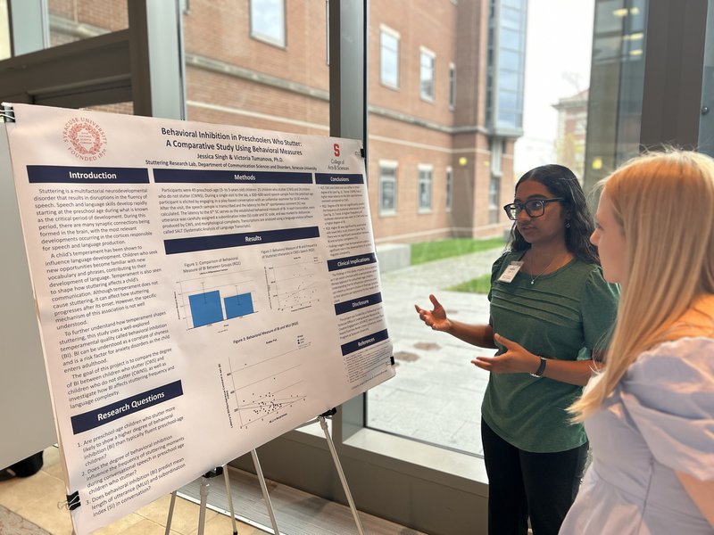 A student presents a research poster to a board member