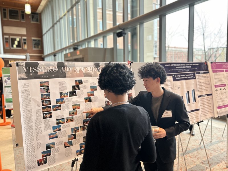 A student presents a research poster to a board member