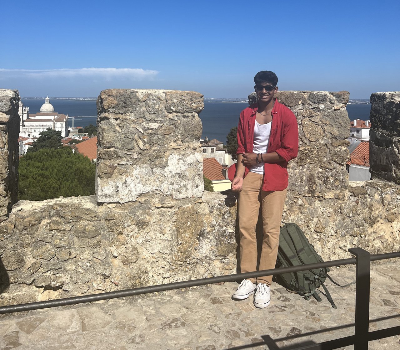 Person standing atop a castle overlooking water.
