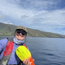 Julia Zeh holding a suction cup tag aboard a boat on the ocean.