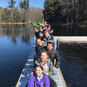 The 2021 SUSTAIN cohort posing on a dock with a lake in the background at Camp Talooli .