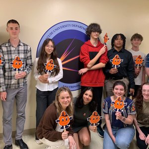 Group of people holding orange mascot signs.