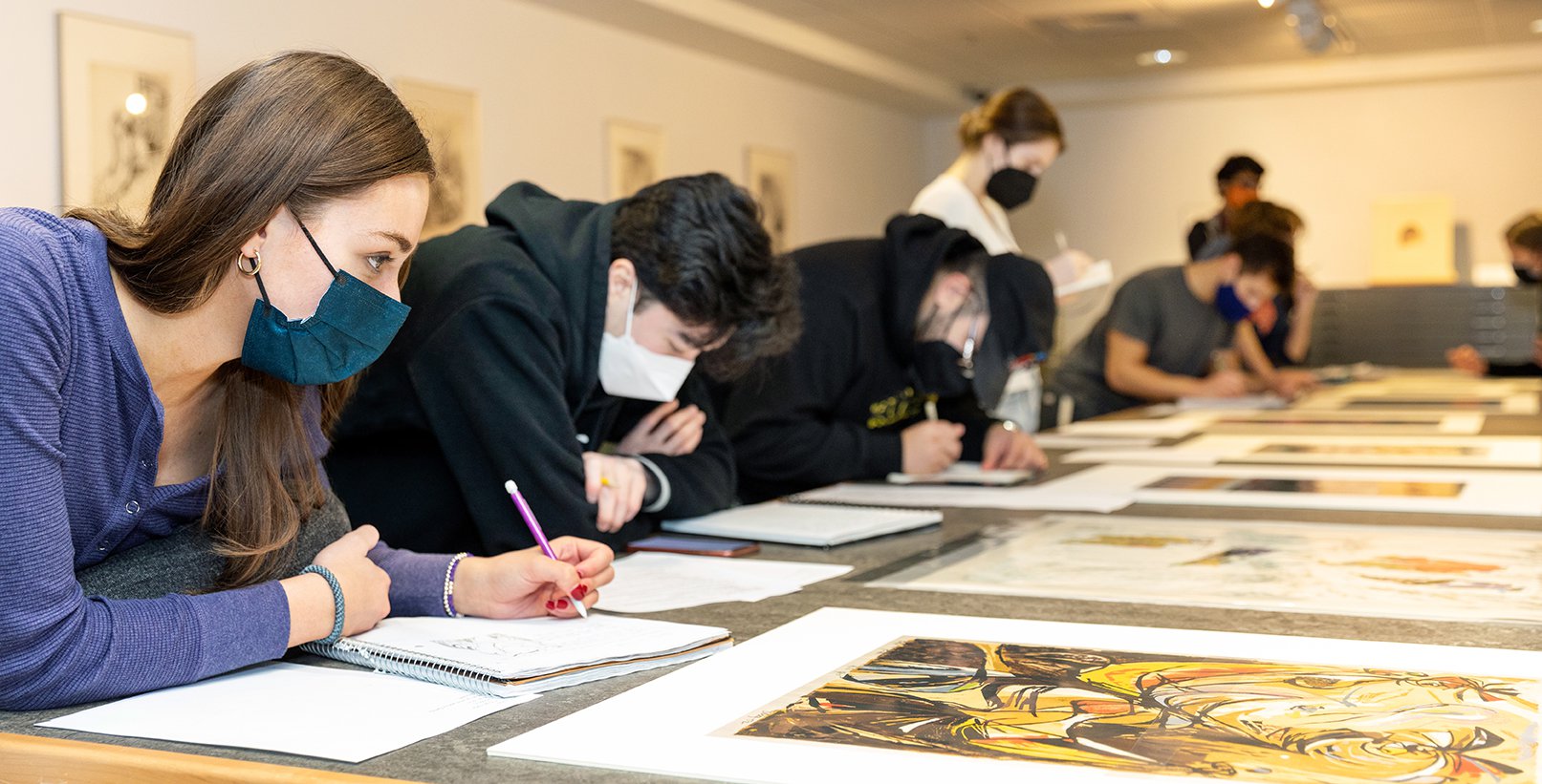 Students studying art work in a museum