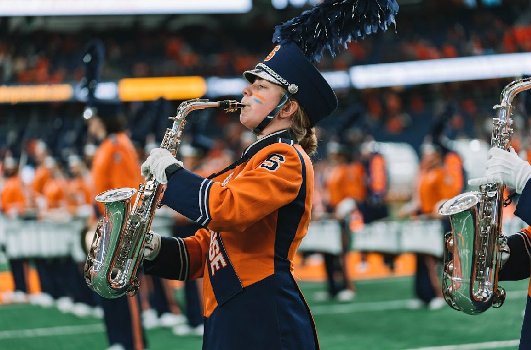 Person playing a saxophone on a football field.