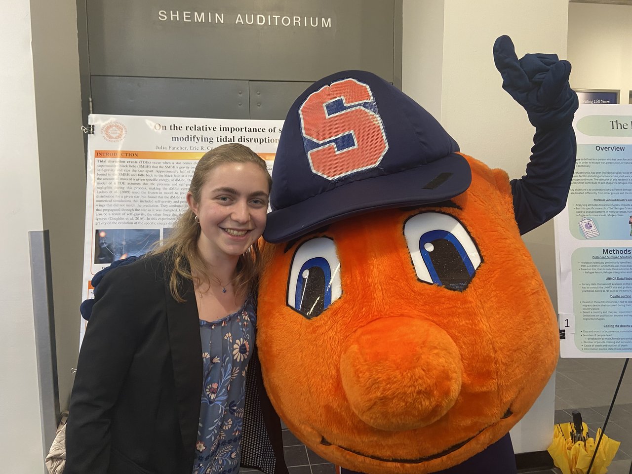 Woman standing with an orange mascot.