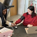 One student takes another's blood pressure in a classroom lab