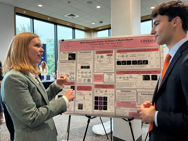 Student and professor discussing their research in front of a poster.