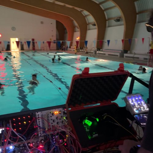 Person with a synthesizer beside a pool.