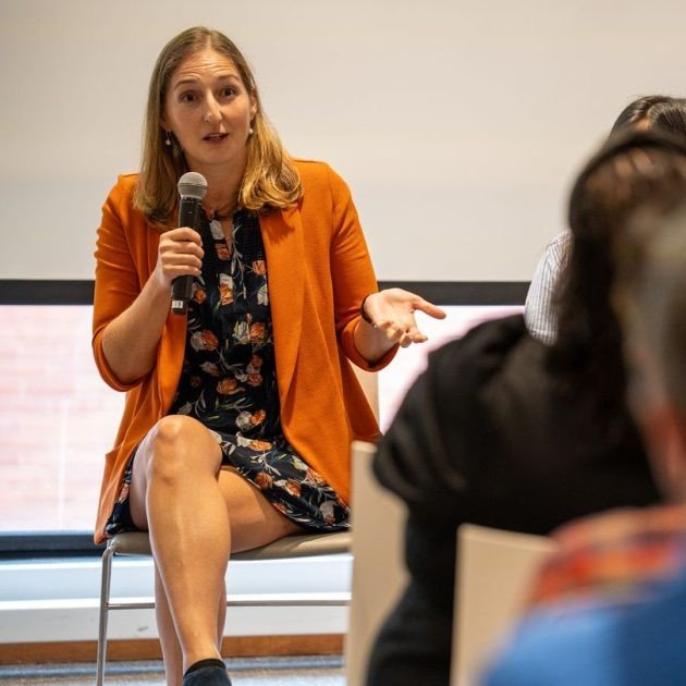 Person with a microphone speaking to an audience.
