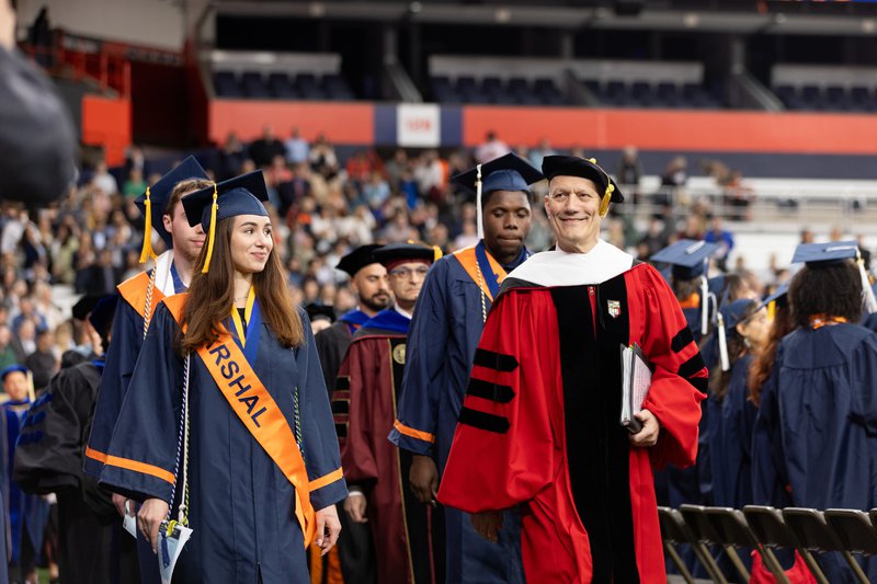 Master of Ceremonies Gerald Greenberg leads the procession alongside the 2024 College Marshals.