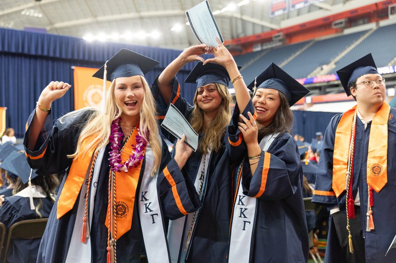 three students posing for a photo with their diplomas at convocation 2024