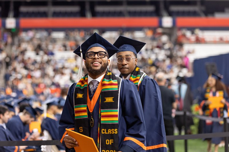 Student looking up at crowd with after receiving their diploma at convocation 2024