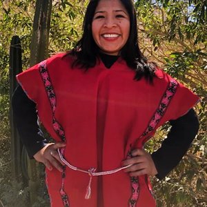 Mariaelena Huambachano smiling in a red, striped poncho