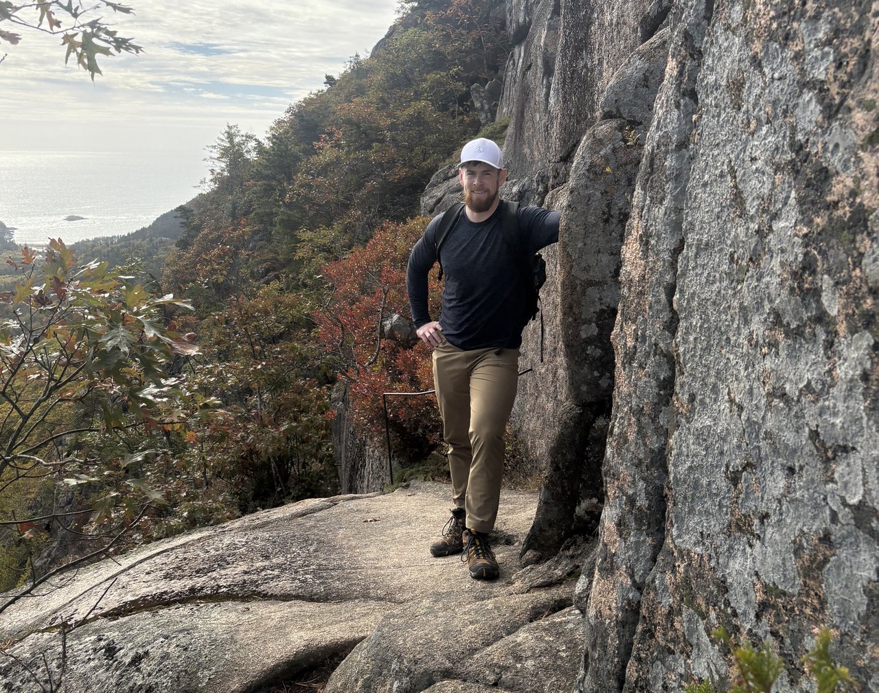 Man hiking standing next to a rock.