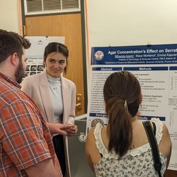 Student explaining research to two people.