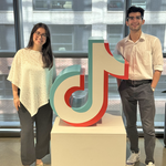 Two people standing next to a TikTok statue.
