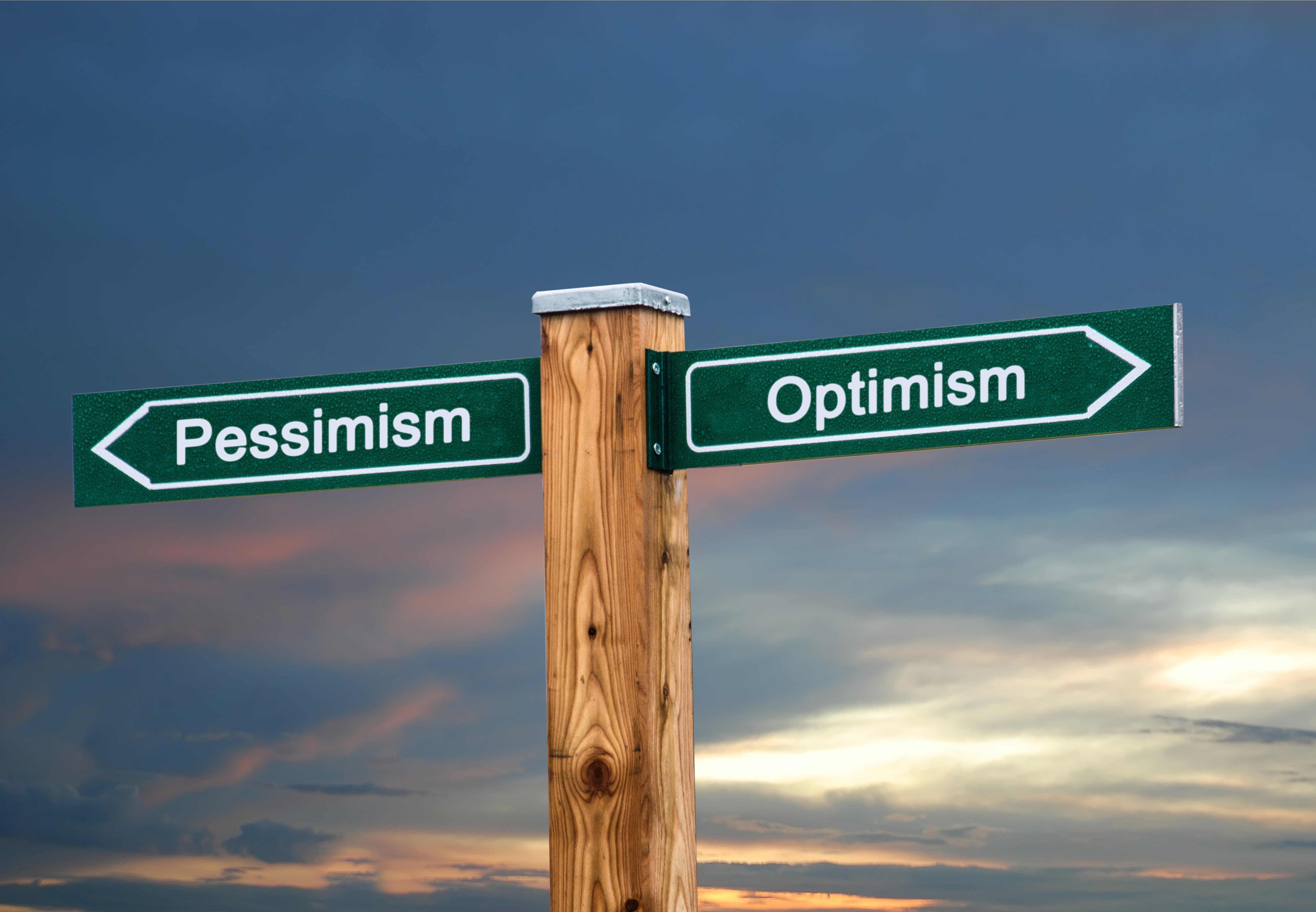 Crossroad with pessimism sign pointed one way and optimism the other way.