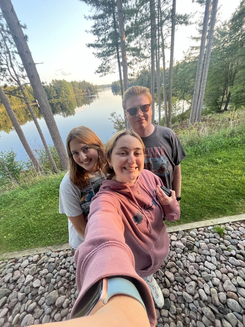 3 Coronat scholars pose in front of a lake