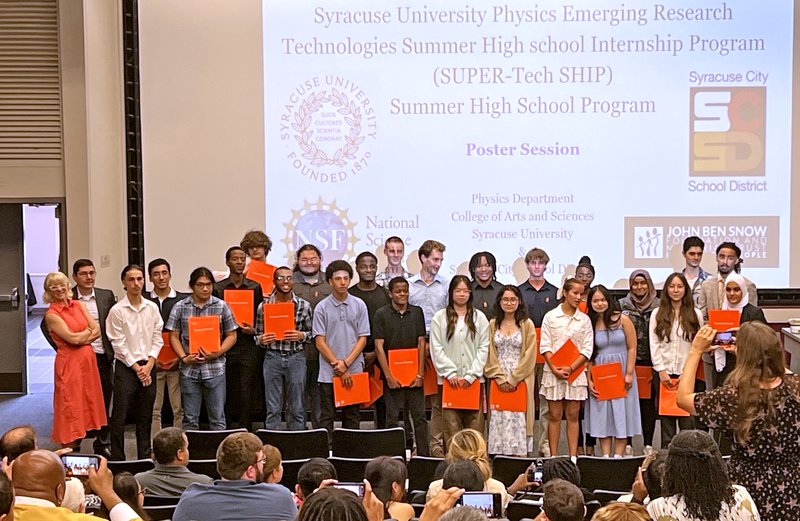 Group of people standing in front of a projector screen.