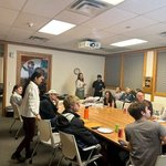 People seated around a table eating pizza.