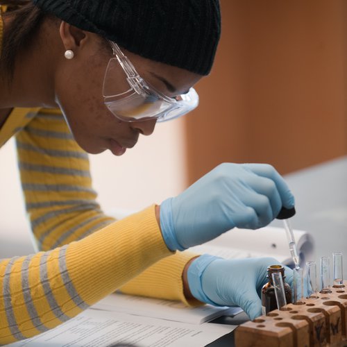 Student with beakers and other lab equipment.