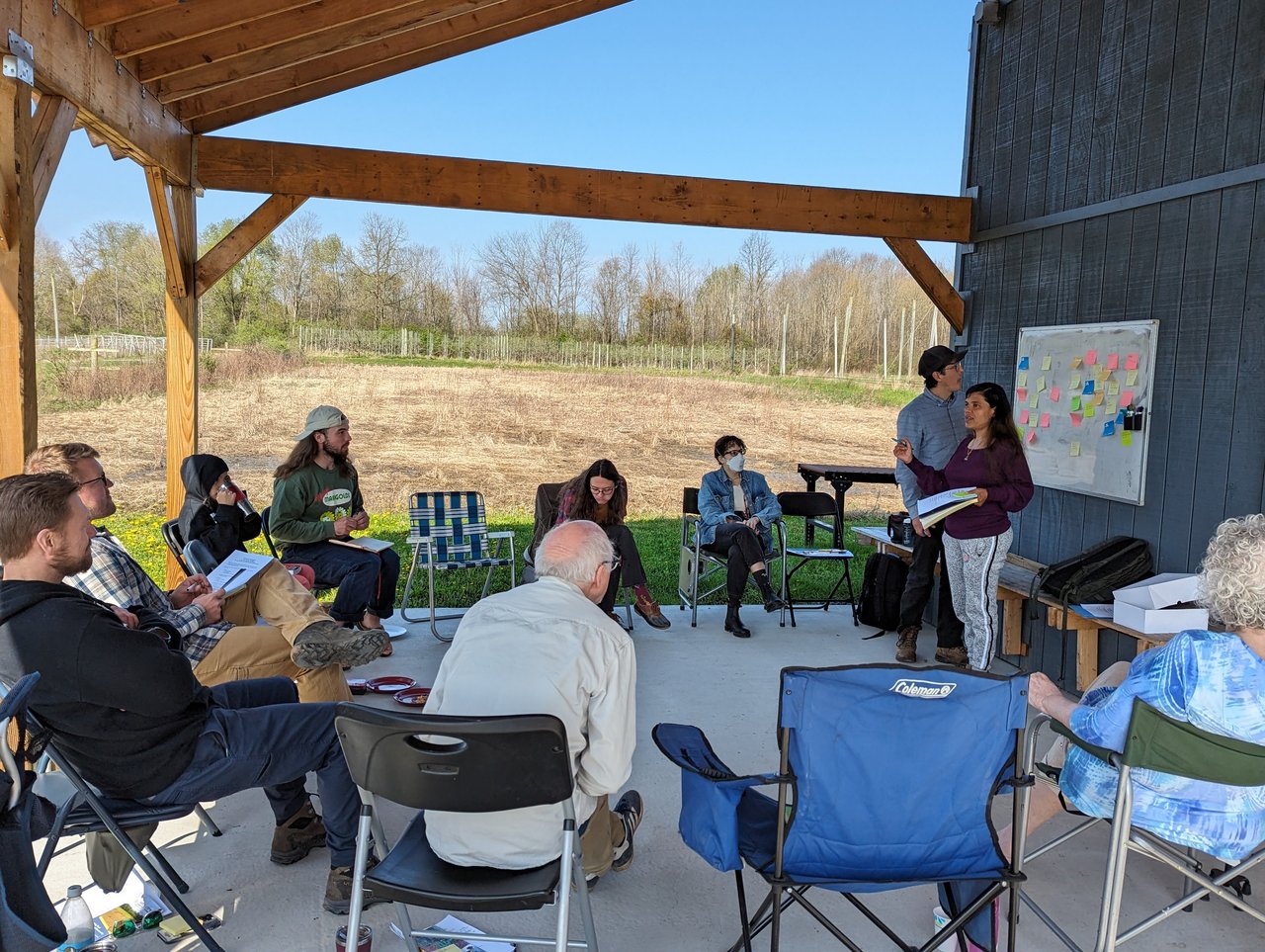 Group of people seated in a circle on a farm.
