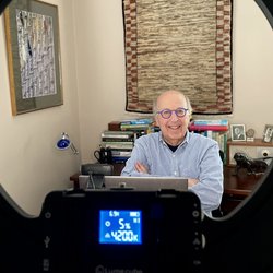 Person wearing glasses with a circlular light in the foreground.