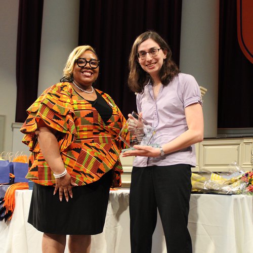 Two people standing together holding an award.