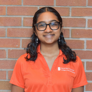 Woman wearing an orange shirt and wearing glasses.