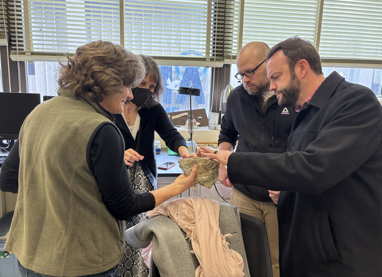 Group of people holding a fossil.