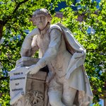 William Shakespeare marble statue with trees in the background.