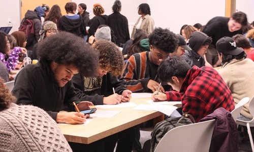 Students sitting at a table writing.