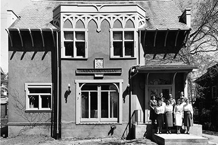 Brewster House, with four people posed on its porch.