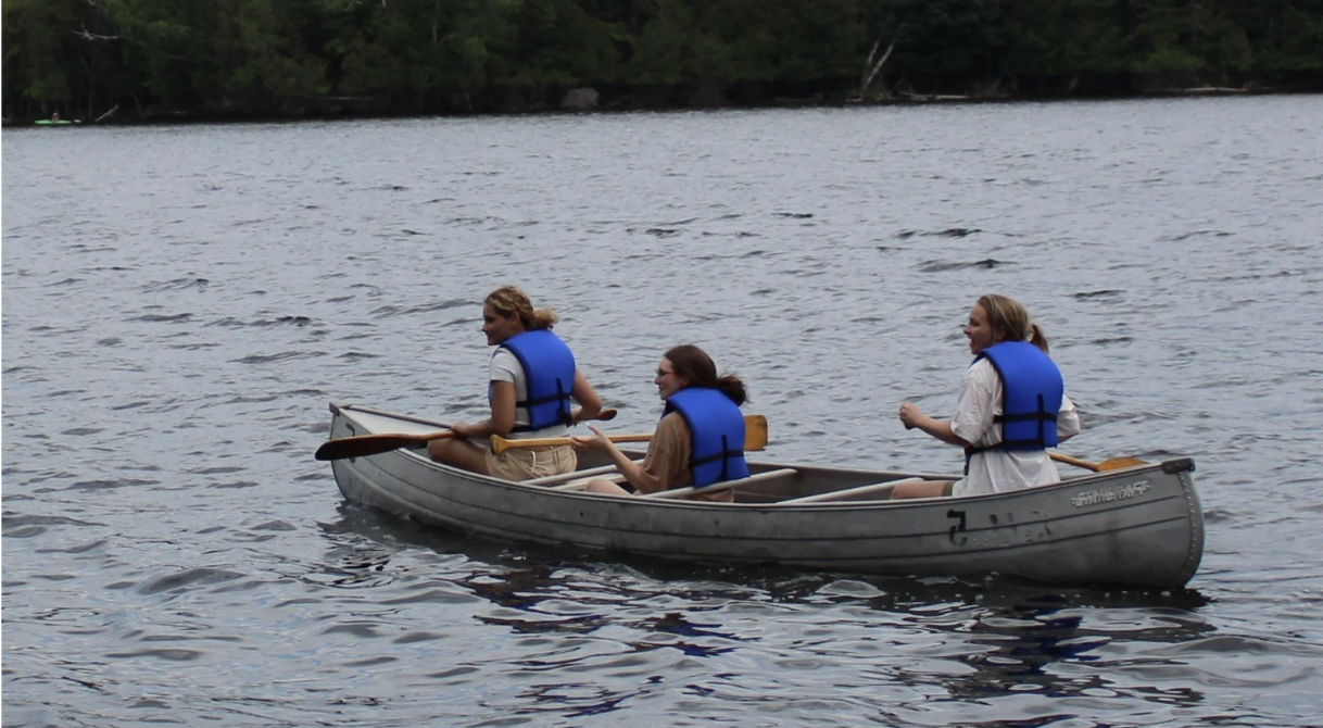 Three people paddling in a canoe.