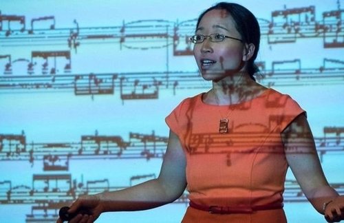 Eugenia Cheng standing in front of a screen.