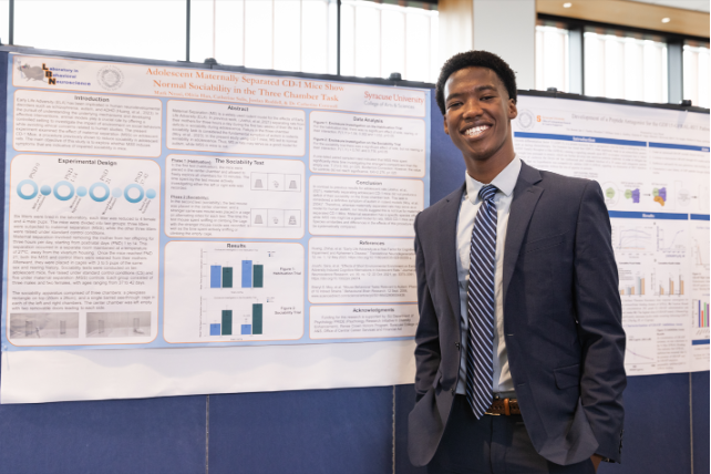 Student posing with research poster