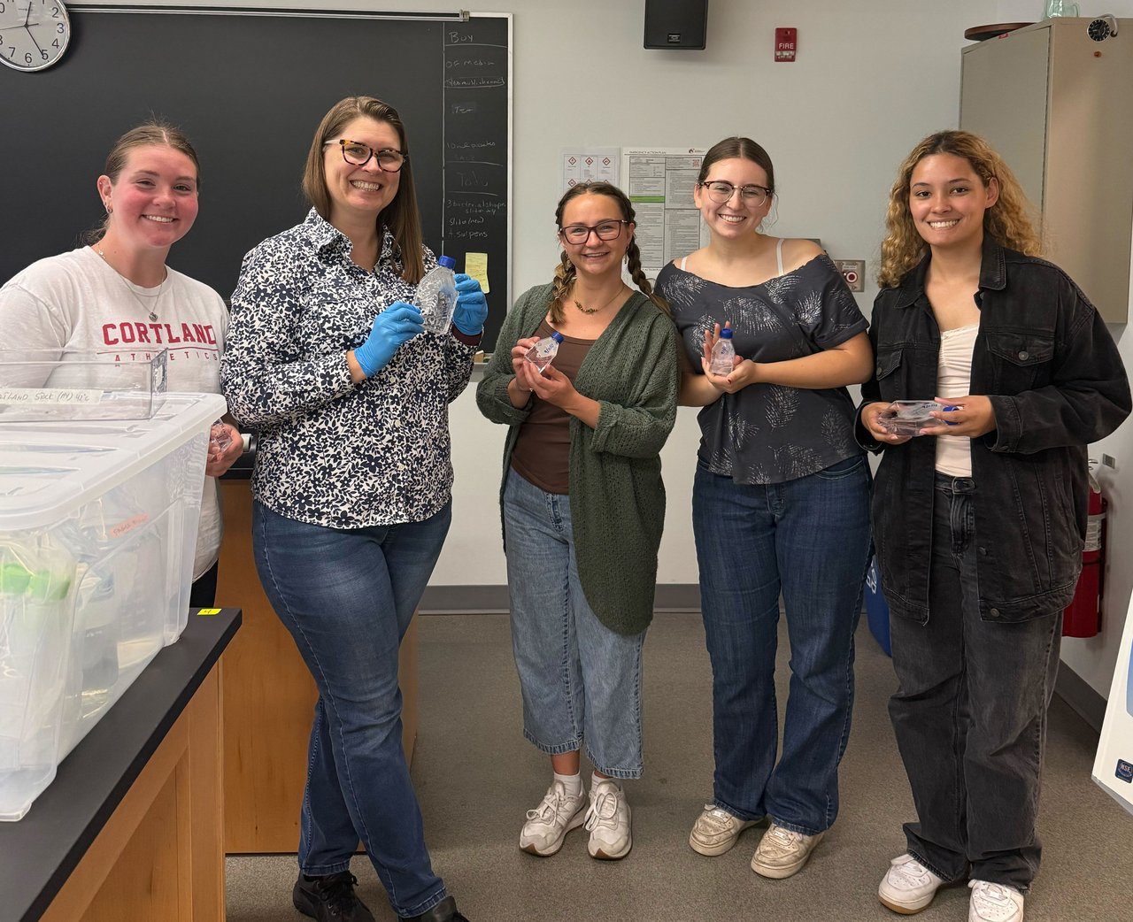 Five people holding scientific samples in a lab.