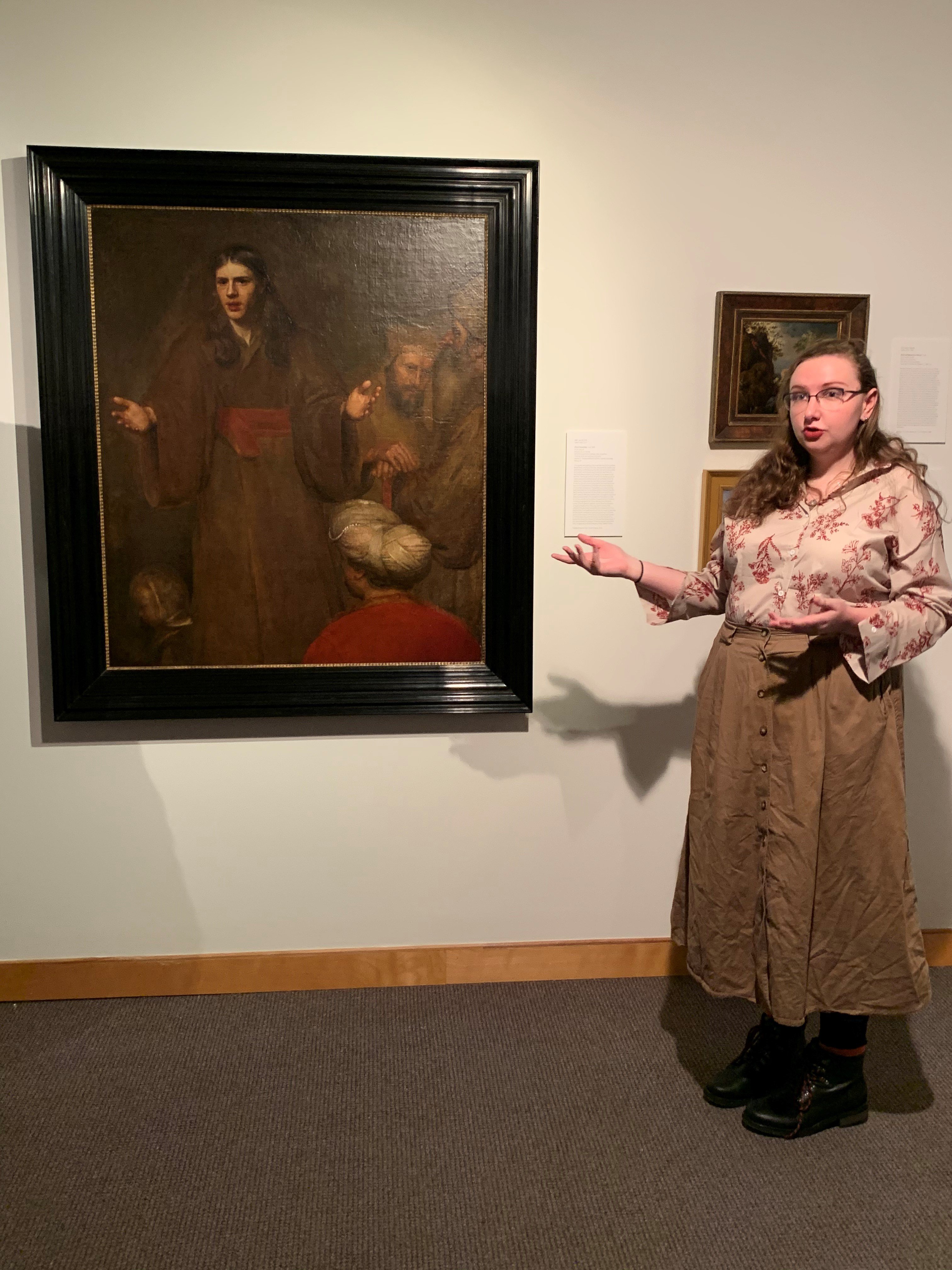 Elisabeth Genter lecturing in front of a painting in a museum.