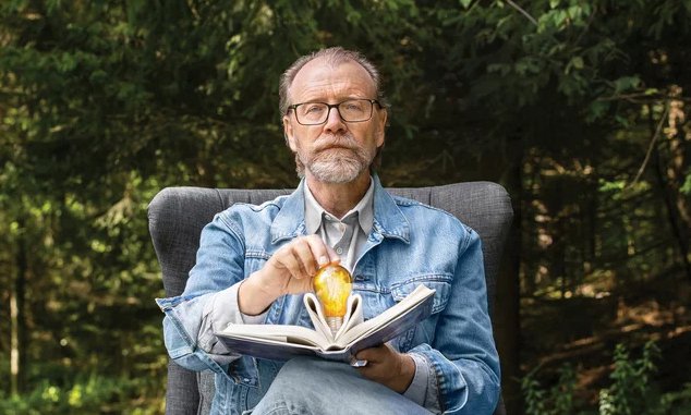 George Saunders holding an open book.